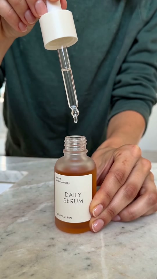 Close-up of a cosmetic serum bottle and its dropper in Ava’s hands.